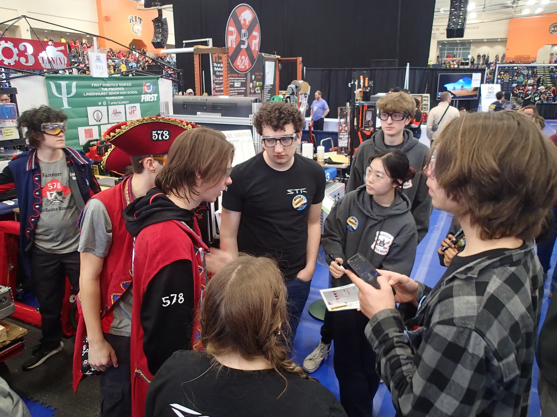 Students and a mentor talking through a design with another team at a competition