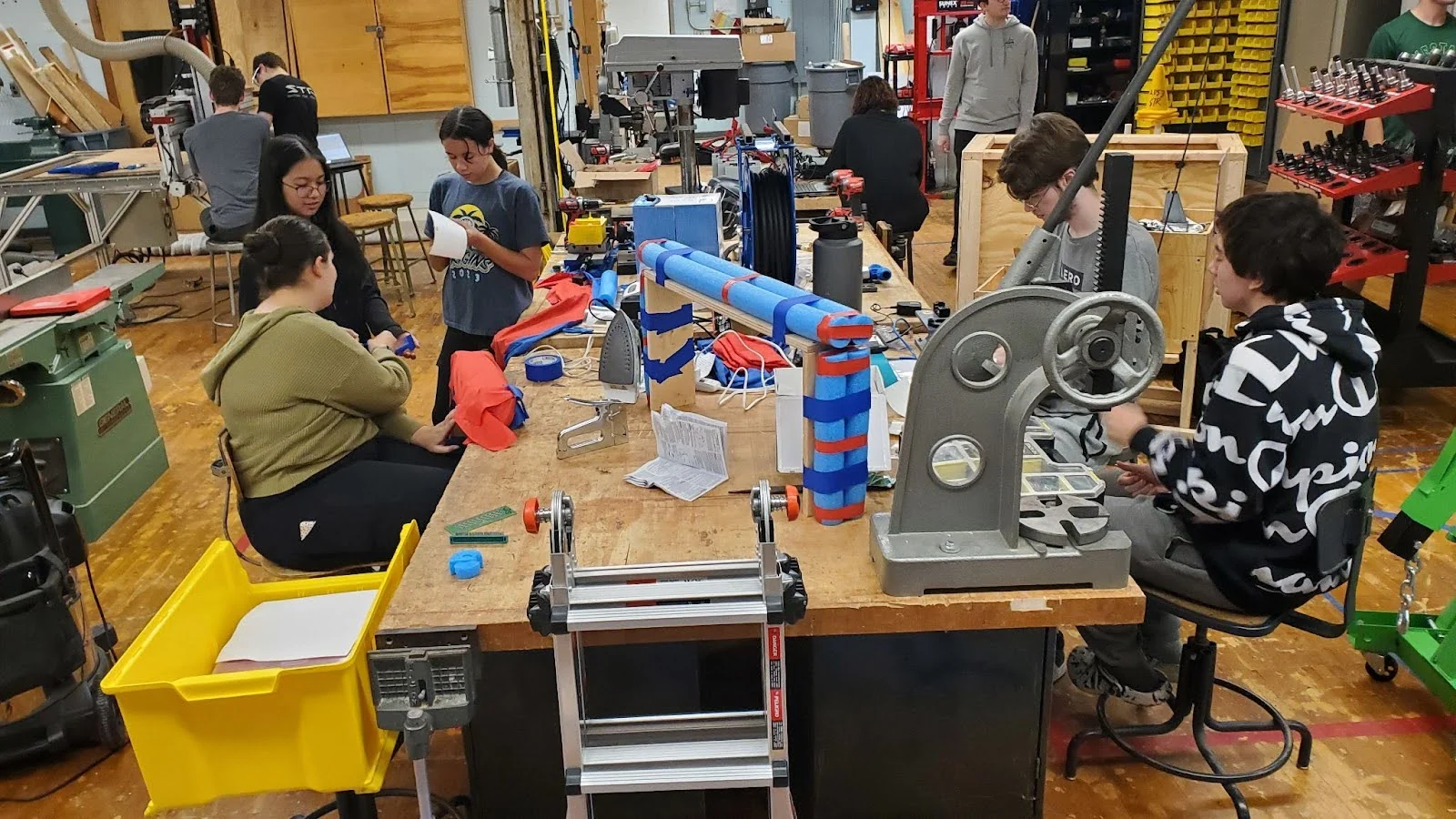 Students working around a bench in the shop during a build meeting